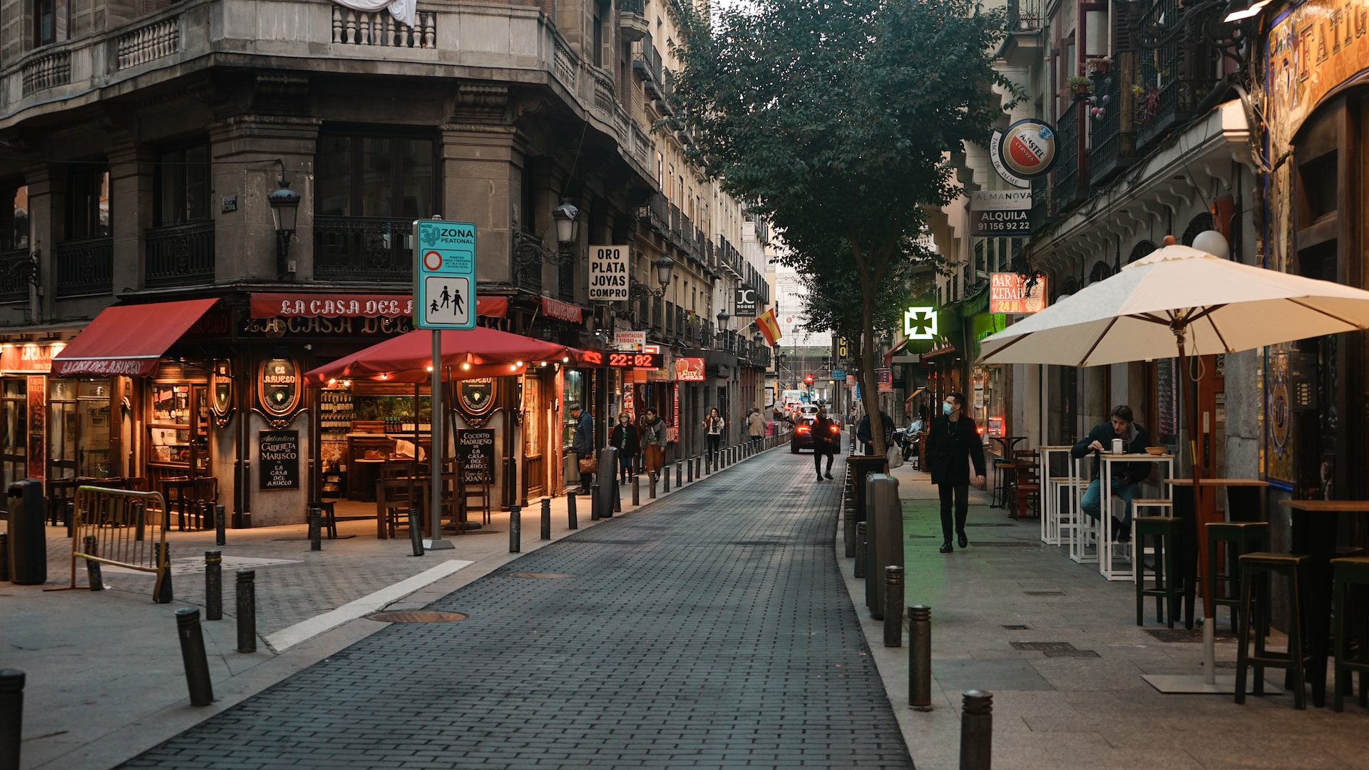 Quiet cobbled city street with cafe terraces and old buildings
