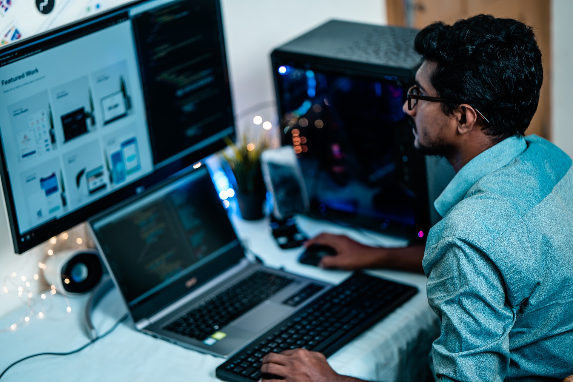 Man working at a computer with a monitor and laptop