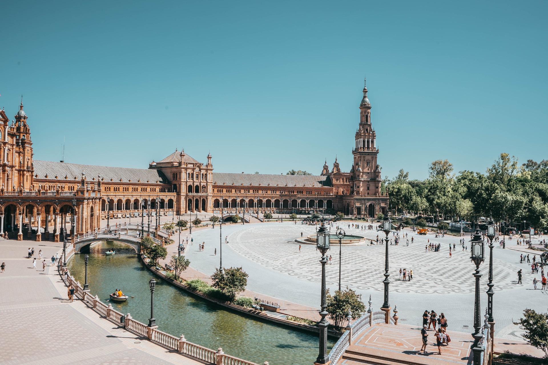 Historic plaza with a canal and ornate towers under a clear blue sky