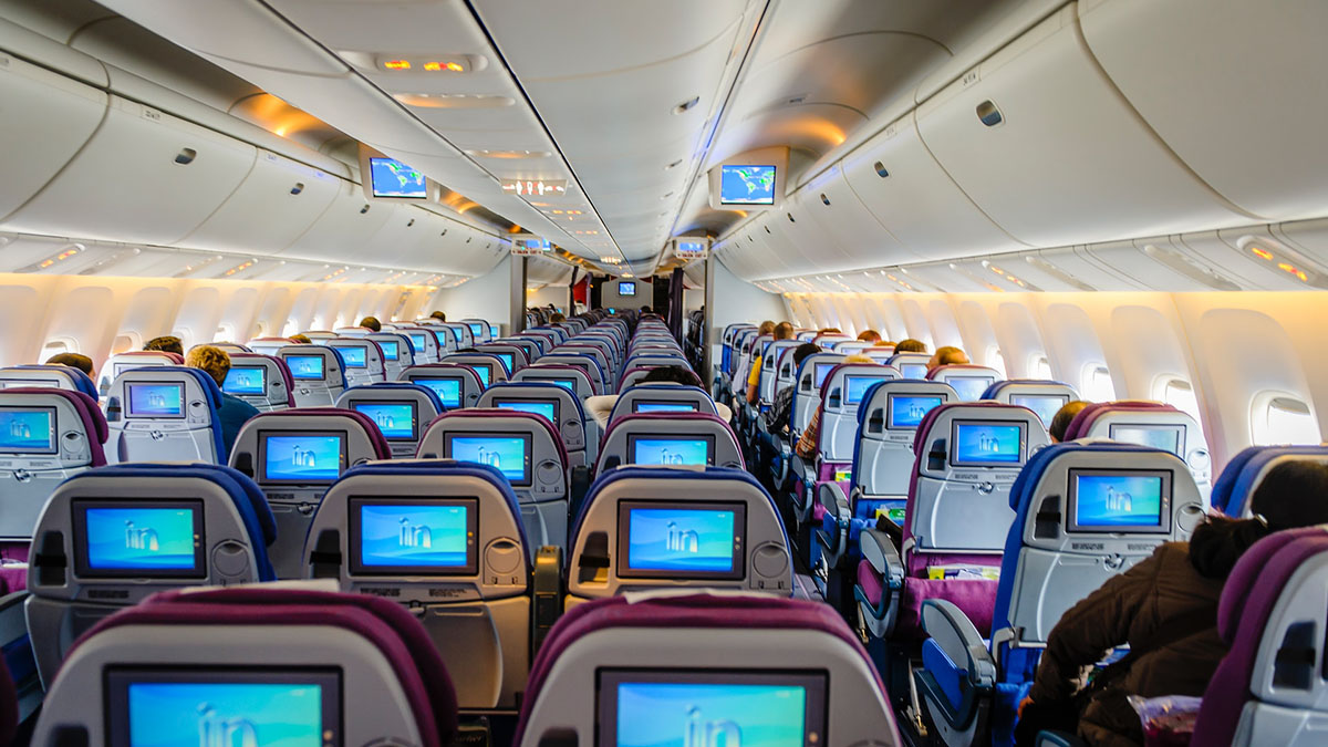 Passenger cabin of an airplane with rows of seats and screens