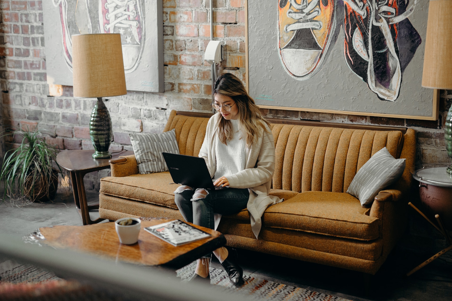Woman working on a laptop on a sofa in a loft