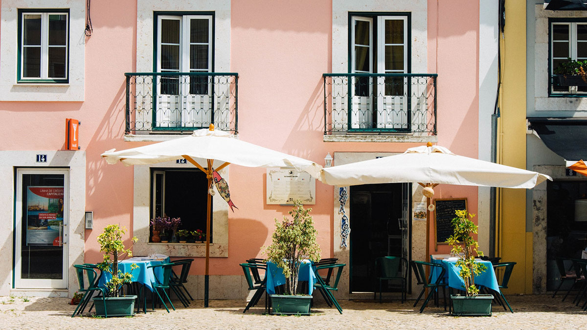 Pink building with balconies and a cafe terrace in Portugal