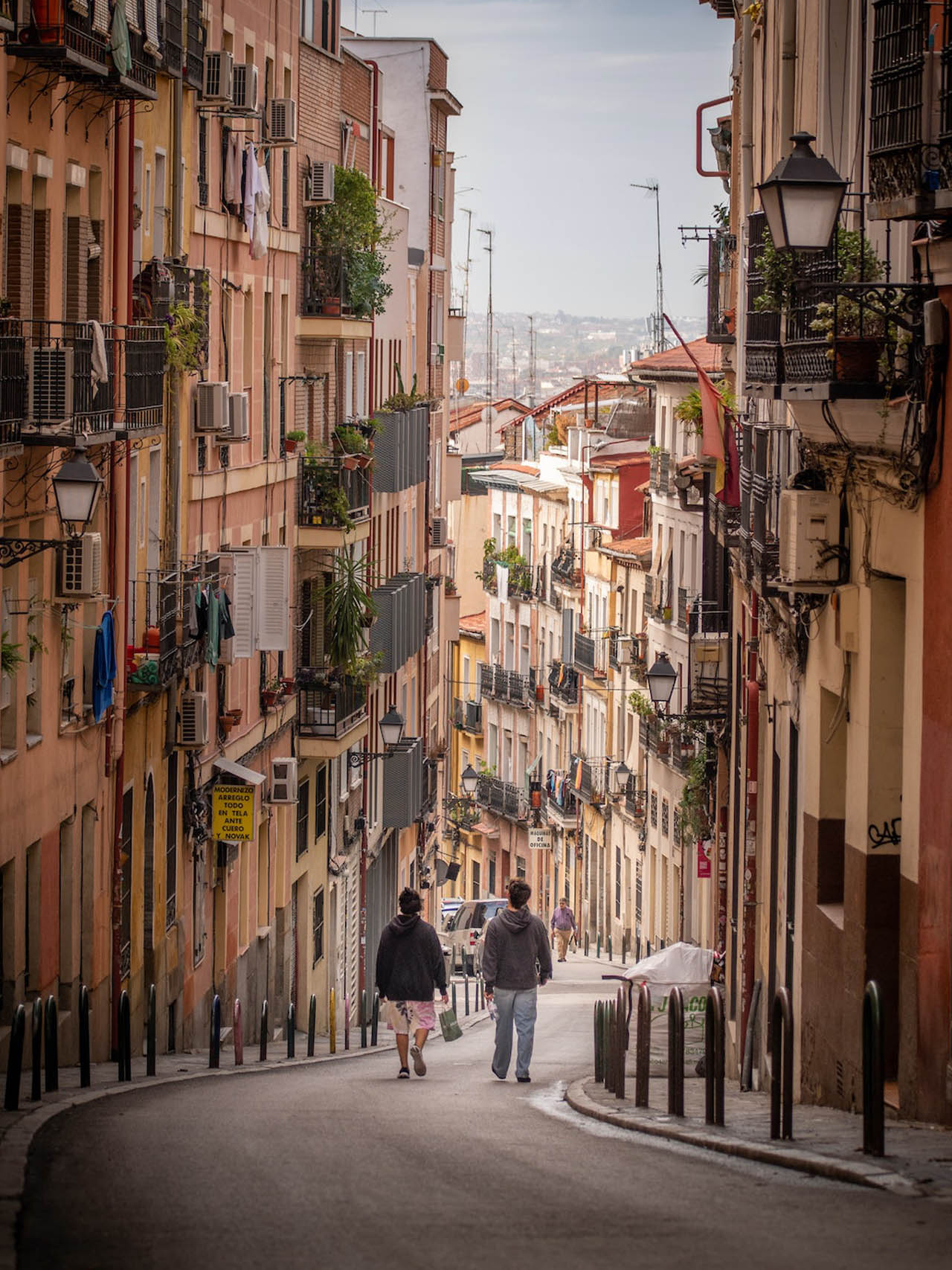 Steep narrow street with balconies and two people walking