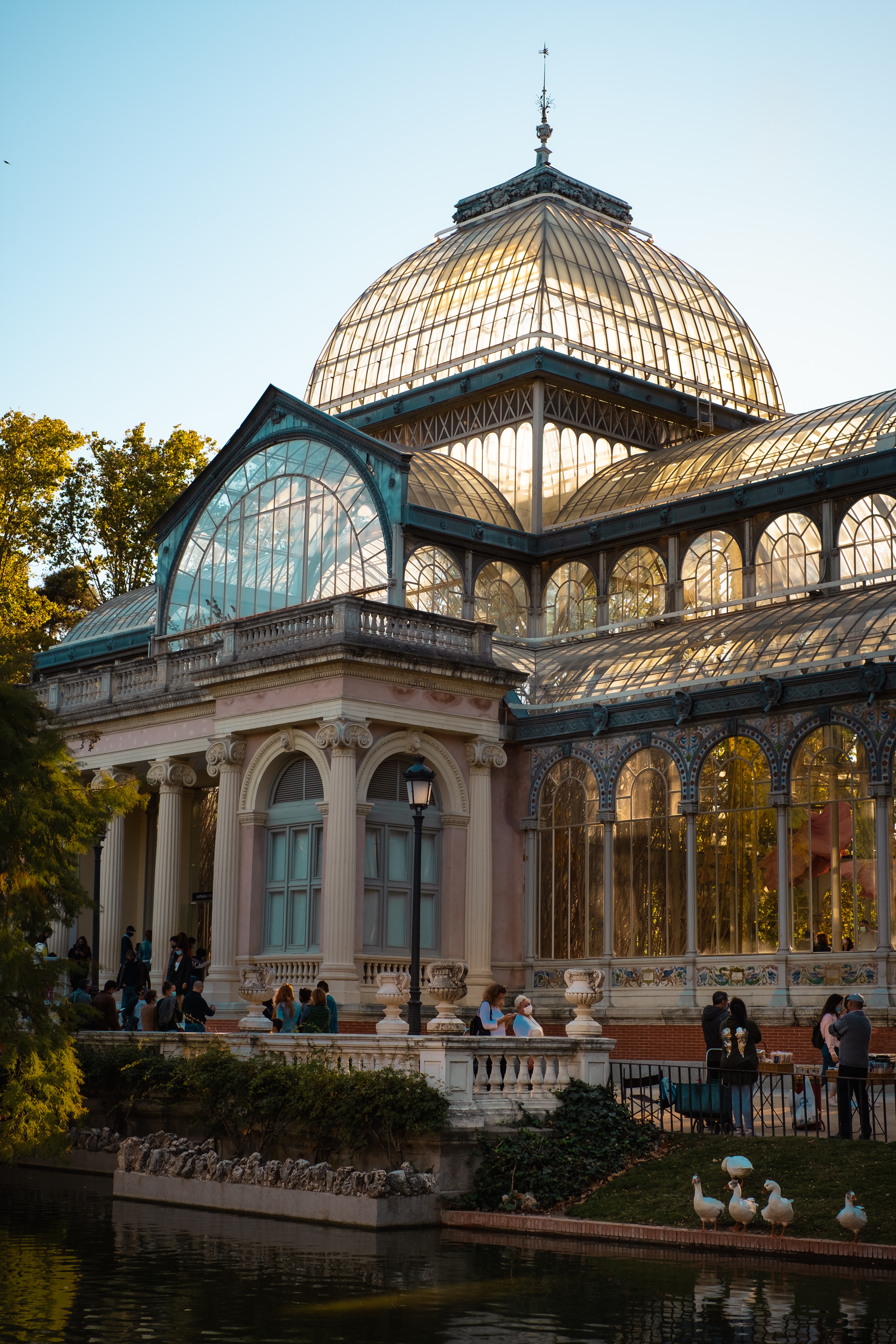 Glass-and-iron palace with a dome beside a pond with ducks