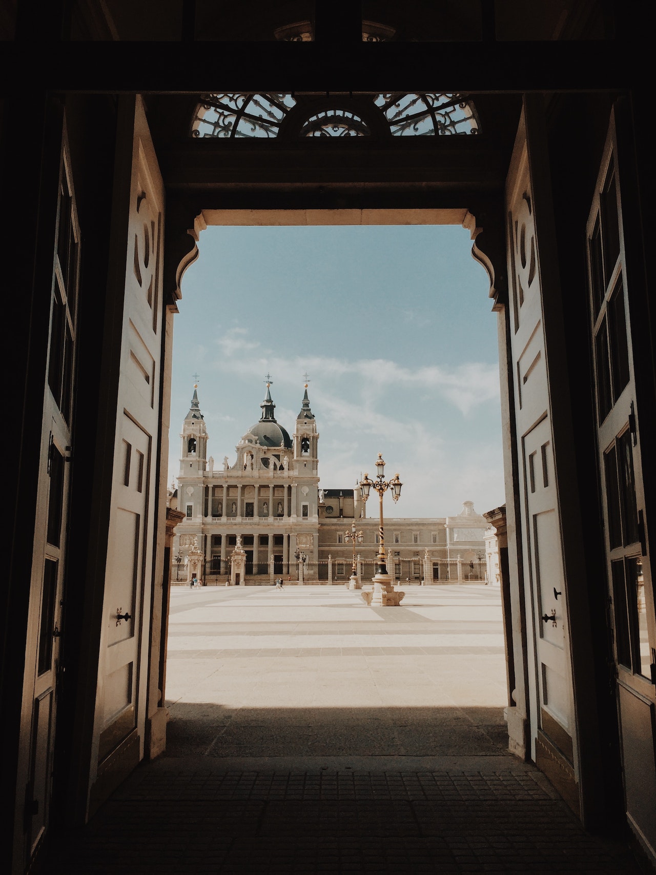 Open wooden doors framing a view of a cathedral across a palace square