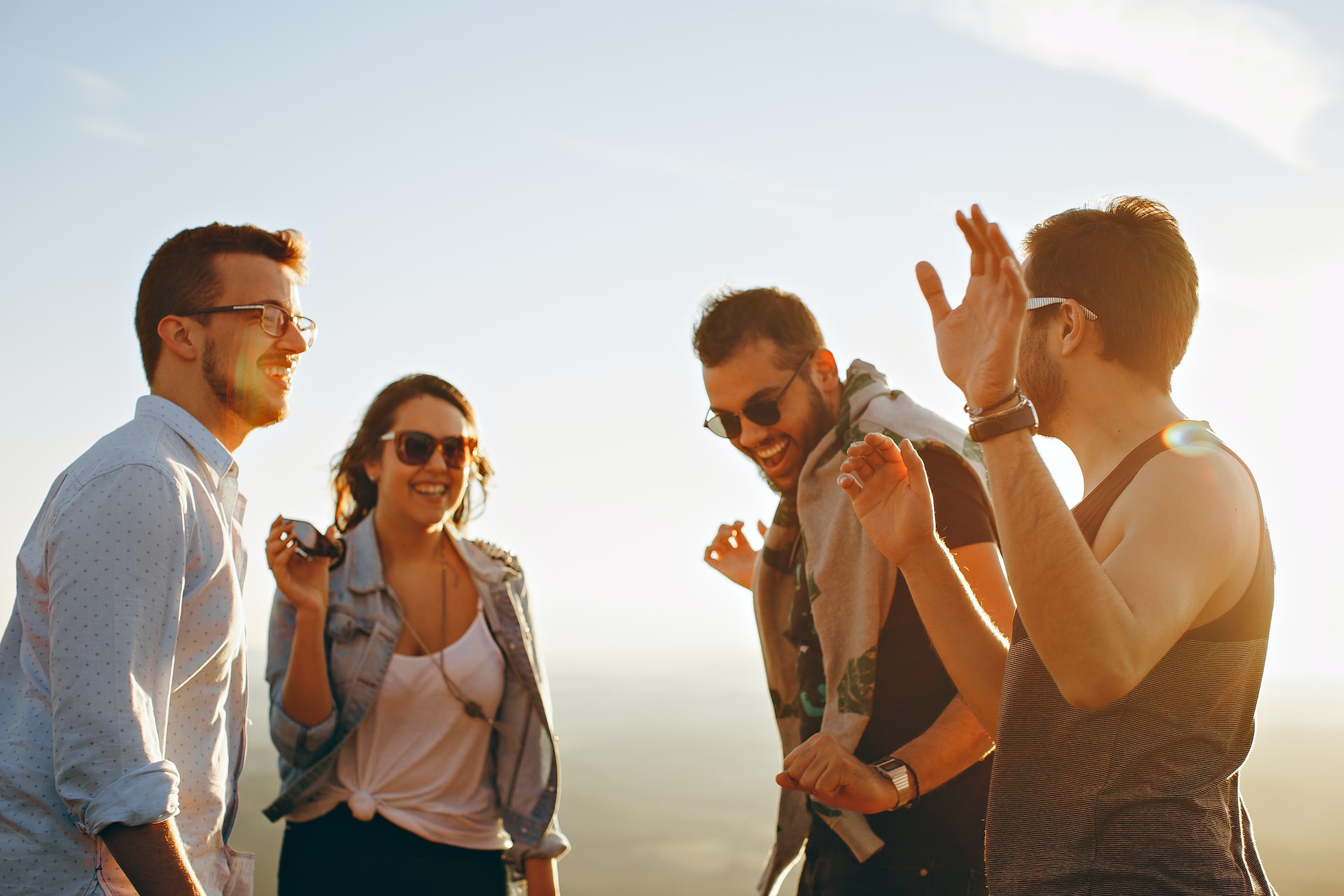 Group of friends laughing together outdoors at sunset
